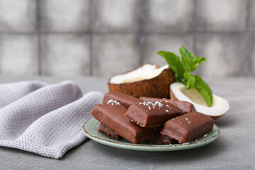 Plate with tasty chocolate covered coconut candies on table