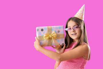 Happy little girl with Birthday gift box on purple background