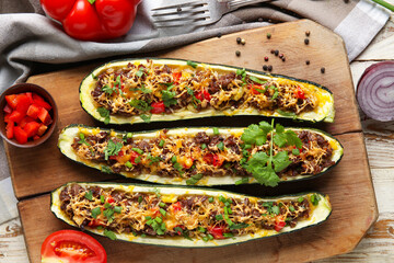 Board with meat stuffed zucchini boats on light wooden background