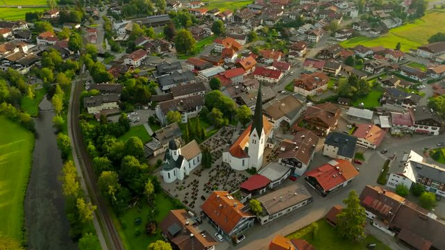 St. Verena in Fischen im Allgaeu, Bavaria, Germany is picturesque Alpine village. From above it reveals stunning views of historic church, countryside and summer landscapes bathed in sunset light. 