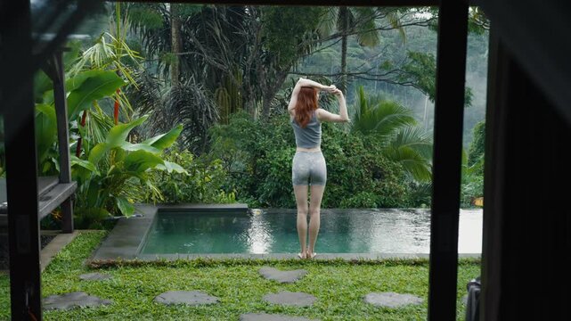 beautiful red-haire gitl doing stretching in the morning witho green jungle background on Bali