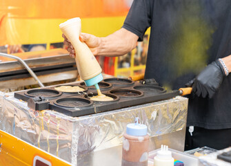 The man drop tart on pan block for made 10 won coin snack.