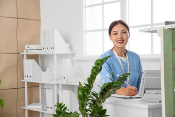 Female Asian medical intern working at reception in clinic