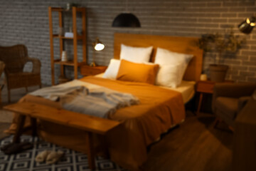 Blurred view of bedroom with glowing lamps and wooden bench at night
