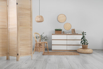 Interior of living room with wooden folding screen, chair and commode