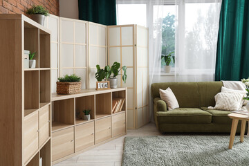Interior of stylish living room with folding screen, sofa and shelf unit