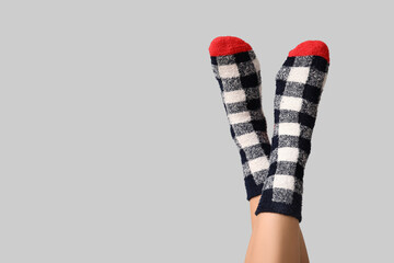 Legs of young woman in warm checkered socks on grey background