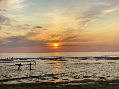 Surfers enjoying the stunning sunset at Les Sables d'Or beach in Anglet, France.