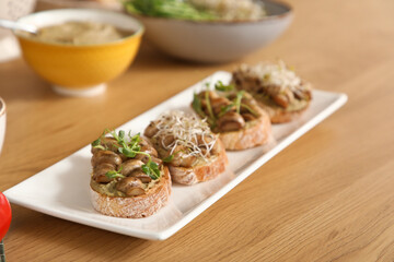Plate with tasty vegan bruschettas on table in kitchen, closeup