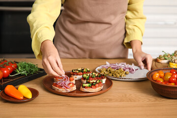 Woman cooking vegan bruschettas at table in kitchen, closeup
