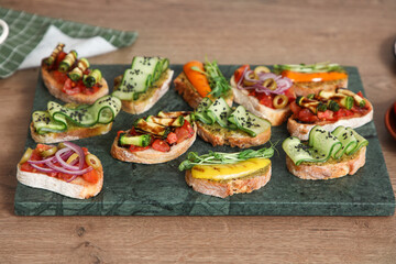 Board with tasty vegan bruschettas on table in kitchen, closeup