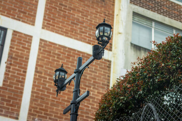 Street lamps illuminate a brick wall in an urban neighborhood during early morning hours