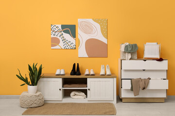Interior of stylish dressing room with stand, commode and paintings