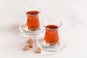 Glasses of Turkish tea with sugar cubes on white background