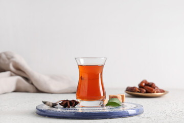Glass of Turkish tea with star anise, leaves and sugar cubes on white background