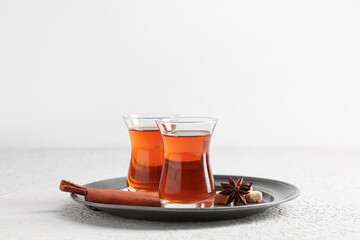 Tray with glasses of Turkish tea, sugar cubes, cinnamon sticks and star anise on white background