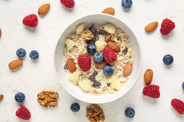Bowl with cornflakes, nuts and berries on white background