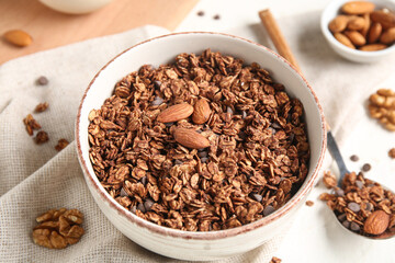 Bowl with chocolate cornflakes and nuts on white background, closeup