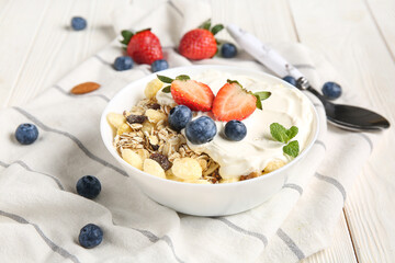 Bowl with healthy cornflakes, yogurt and berries on white wooden background, closeup