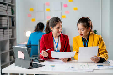 Businesswomen working together analyzing financial documents in modern office