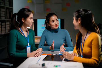 Fototapeta premium Asian businesswomen having meeting using tablet in office at night