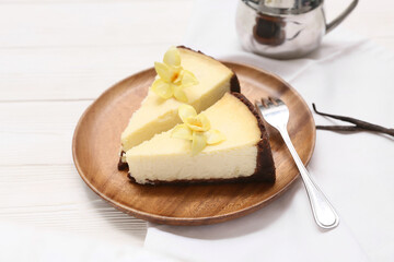 Plate with pieces of sweet vanilla cheesecake on white wooden background