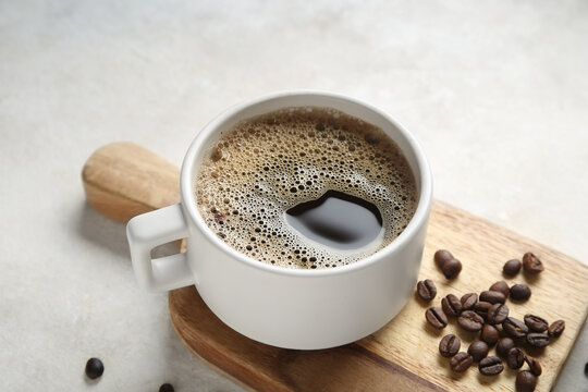 Cup of hot coffee and beans on white background