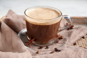 Glass cup of hot coffee with beans and star anise on white background