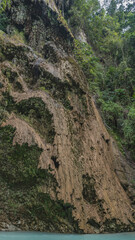 Beautiful tropical waterfall. Thin streams of water flow down the mossy terraces of the slope into the turquoise lake. Green vegetation. Philippines. Cebu. Tumalog Falls.