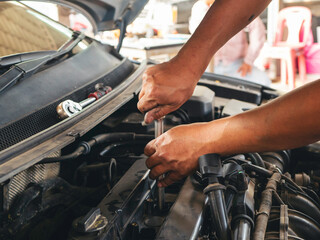 Obraz premium Close up Car Mechanic man hands repairing car auto repair shop. Man hands fixing machinery vehicle mechanical service. open vehicle hood checking up auto mobile. Vehicle Car maintenance engineer.