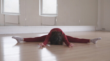 A highly skilled and talented dancer performs a beautifully graceful split in a minimalist studio