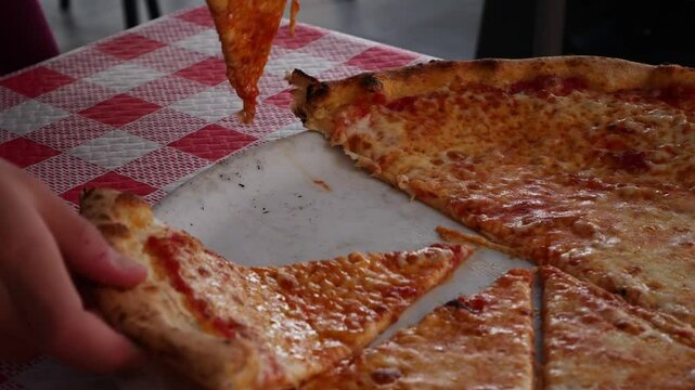 Child separating two slices of Margarita pizza. Slow motion x0,5