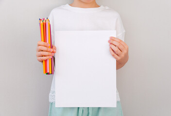 A blank canvas in the girl's hands and colored pencils. Template and mock up for design, copy space