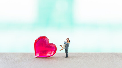 Miniature couple with red heart over blurred background, valentine background idea, love and...