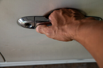 Close-up of a hand opening a car door with a chrome handle, representing transportation, travel,...