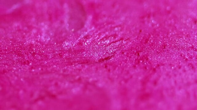Glitter cream fluid. Sparkling flow. Defocused transparent pink color shiny sequin particles bright emulsion wave motion bokeh light texture abstract art background.