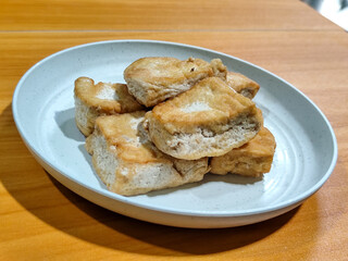 Fried tofu on a white plate. Traditional Indonesian snack.