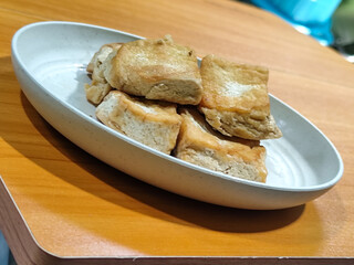 Fried tofu on a white plate. Traditional Indonesian snack.