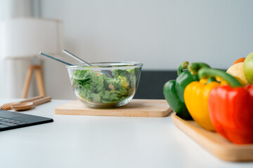 Glass bowl of fresh green salad and colorful bell peppers, promoting a healthy lifestyle and balanced diet