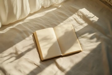 Open blank notebook resting on a soft white bedspread illuminated by warm sunlight in a cozy room during the morning