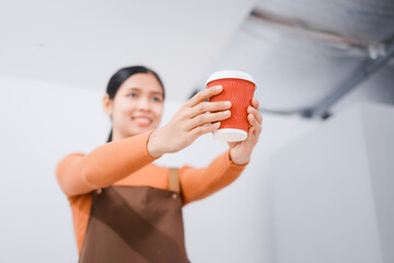 Asian female barista with a beautiful smile, skillfully making coffee in a cozy small shop, creating a warm and welcoming atmosphere for customers in the charming cafe