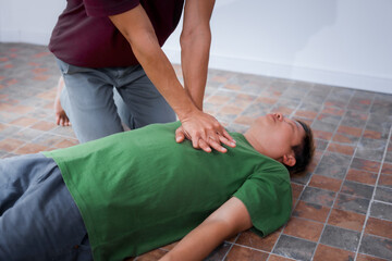 Naklejka premium A man performing CPR on another man lying down, placing his hands on the patient’s chest to ensure safety, monitor heart rate, provide emergency services, and maintain health care and body integrity