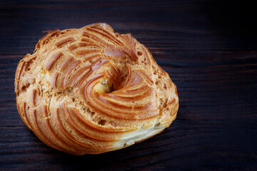 Eclair on a dark wooden background. Profiterole . Eclair in the form of a ring.