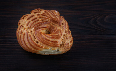 Eclair on a dark wooden background. Profiterole . Eclair in the form of a ring.