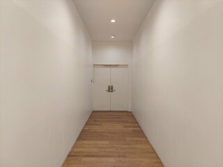 A white door at the end of a corridor with wood flooring