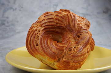 The profiterole cake is on a yellow plate. The eclair is in the shape of a ring.