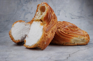 Cut profiterole cake. Eclair with white filling.
