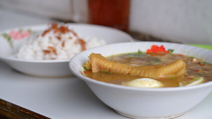 Chicken soup with shredded chicken, chicken feet, eggs, sliced cabbage, vermicelli in broth. Indonesian food.