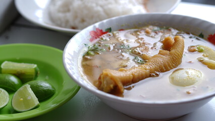 Chicken soup with shredded chicken, chicken feet, eggs, sliced cabbage, vermicelli in broth. Indonesian food.
