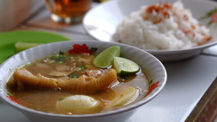 Chicken soup with shredded chicken, chicken feet, eggs, sliced cabbage, vermicelli in broth. Indonesian food.